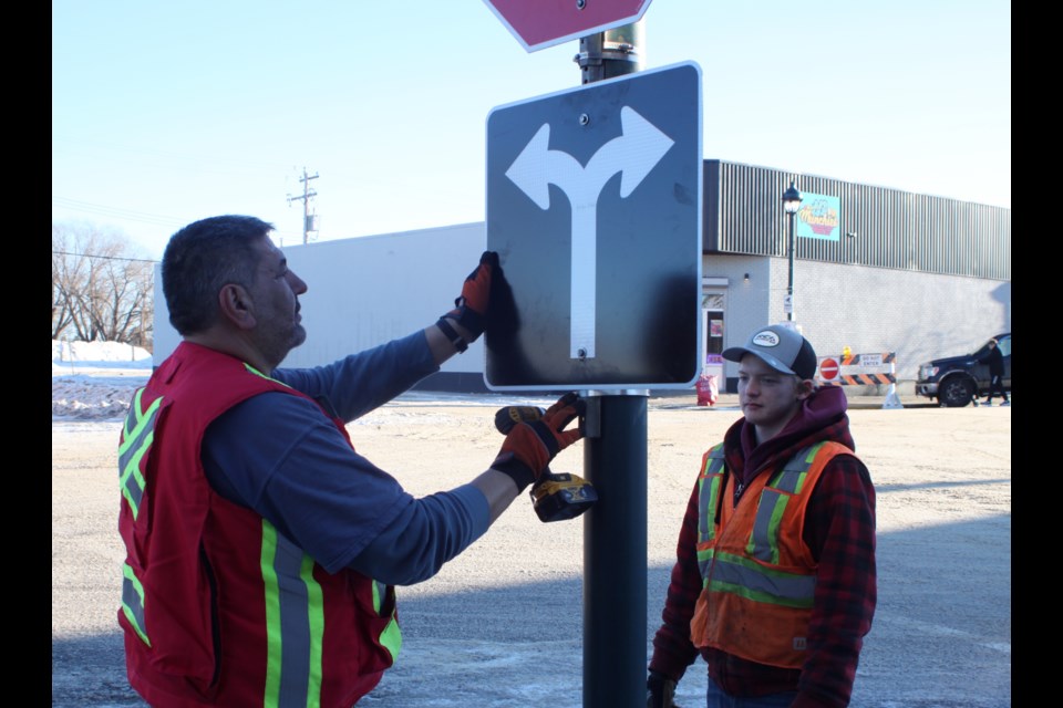 Doug Spence and Evan Ross of Lac La Biche County install a two-directional arrow traffic sign on the corner of 101 Street and 102 Avenue on Jan. 9. / Chris McGarry photo