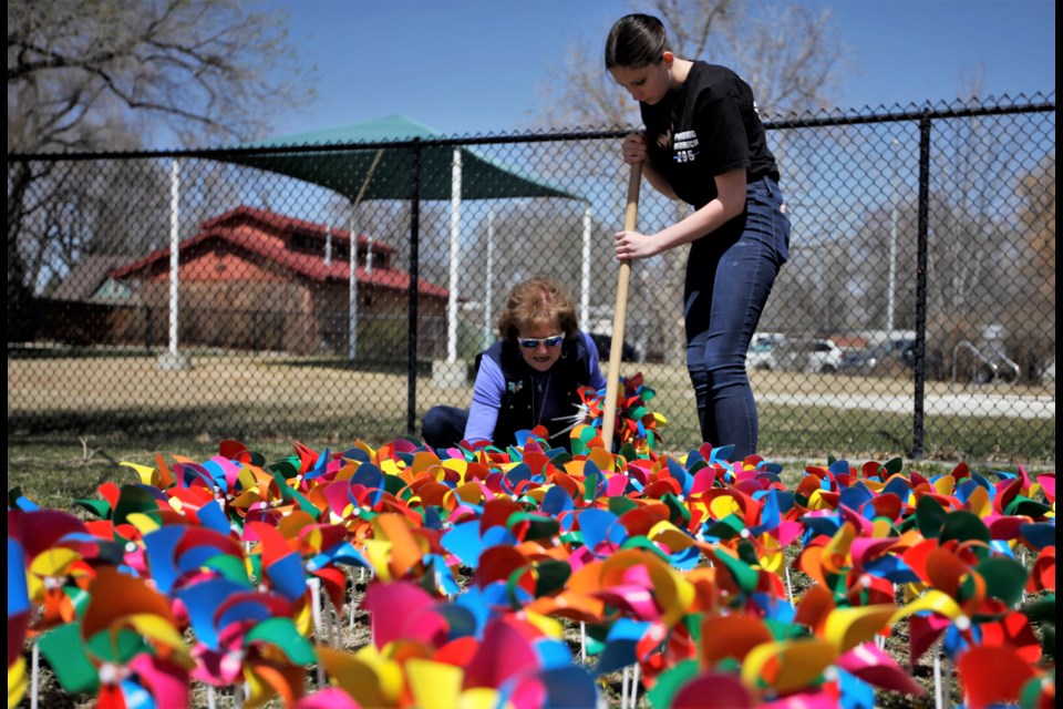 Blue Sky Bridge and community members poke holes to plant pinwheels on Monday at Roosevelt Park. Project Pinwheels raises awareness of child abuse.