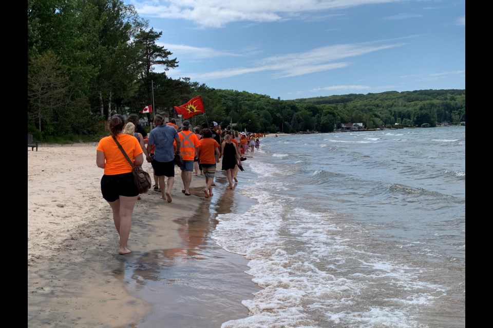 Participants walk along Thunder Beach during an Indigenous rights demonstration on Canada Day.