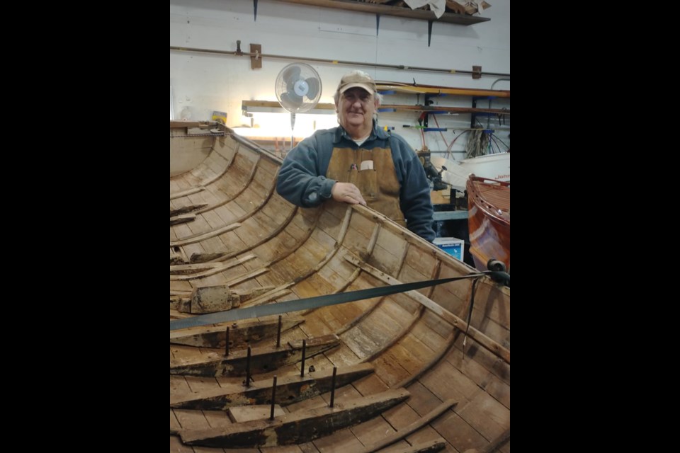 Georgian Bay Heritage League president Basil Lafrenière stands with a boat being restored.