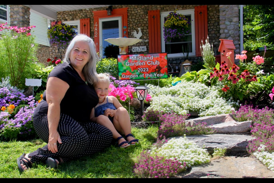 Kathy Paquette's garden at her Midland Avenue home has been chosen as the Garden of the Year by the Midland Garden Club. Paquette is seen with her granddaughter, Scarlett.