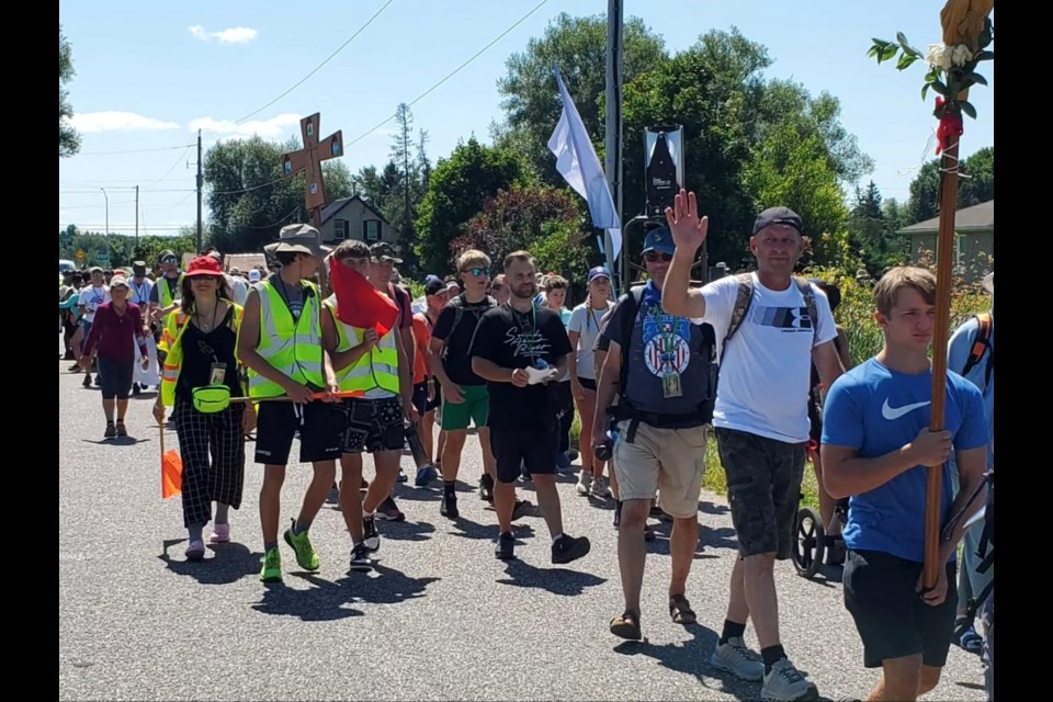 Pilgrims walk along an area road on their way to the Martyrs' Shrine in Midland. The man wearing all black is the brother of slain OPP officer Const. Grzegorz "Greg" Pierzchala.