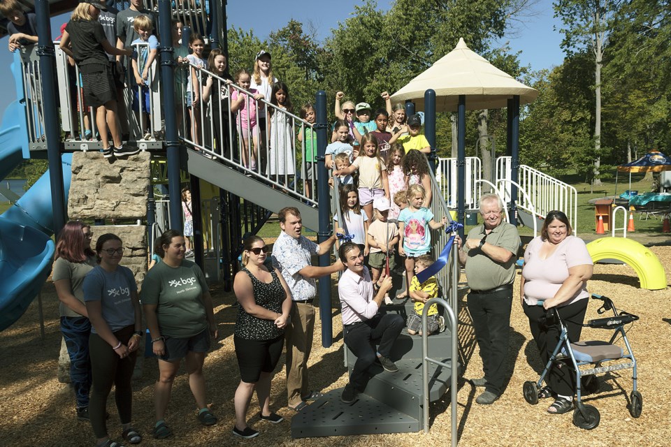 Dozens of children joined Midland Mayor Stewart Strathearn (green shirt) and Simcoe North MP Adam Chambers (holding a large pair of scissors) on Tuesday to cut the ribbon commemorating new playground installations throughout the town, like this one in Little Lake Park.