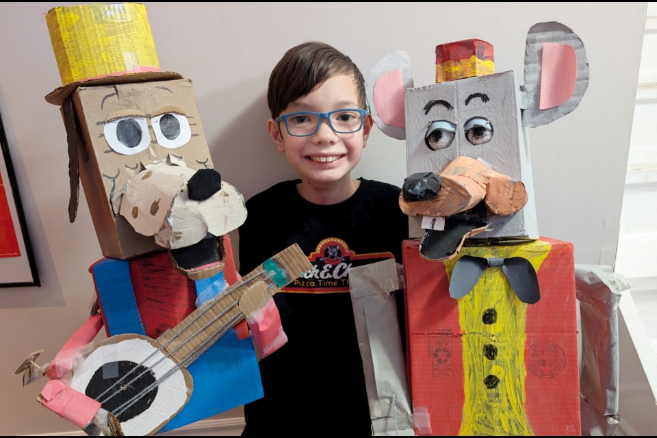 Young Milton puppet maker Cole Magallanes with two of his many Chuck E. Cheese character creations.