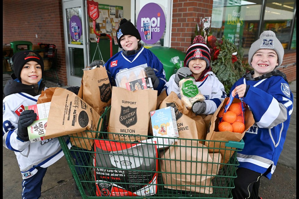 Milton Winterhawks U10 A players (from left) Yusuf, Graham, Joshua and Caleb load up a cart with food donations out front the Food Basics during the annual Milton Food Drive.