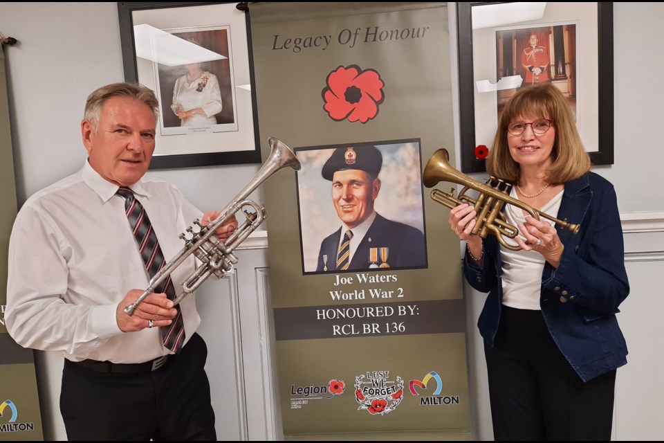 Jim Gibbons and Susan Waters Devaan stand beside the Legacy of Honour banner in tribute to their grandfather Joe Waters while holding the family's trumpet and cornet that have been donated to the Milton Legion.