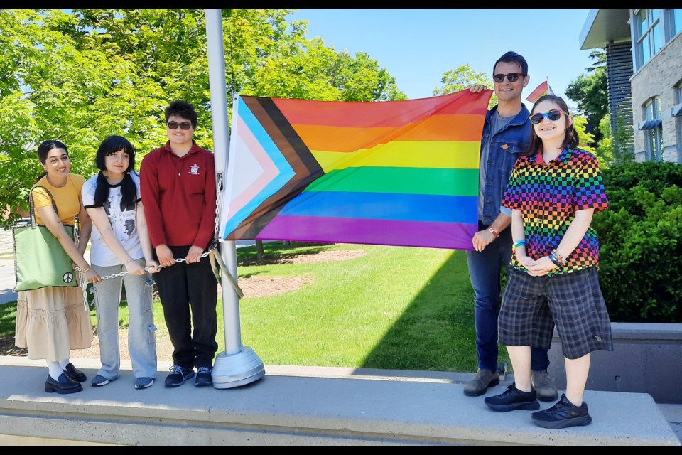 From left, Jason Sullivan, Muskan Arif and Anna Aiello, MP Adam van Koeverden and Andrew Clarida raise the Pride flag.