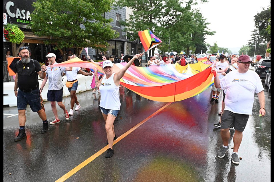 Melanie Tremills, founder of PRISM Halton and event organizer, didn't let a short heavy downpour dampen the fun as she leads the parade, helping carry a giant Pride flag.