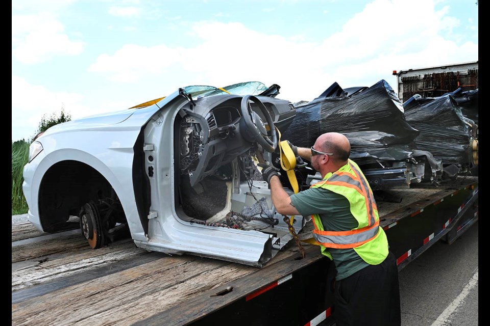 A tow operator secures the front portion of a stolen Volkswagen after Halton Police detectives from the Regional Auto Theft Task Force executed a search warrant at a rural Milton property, recovering close to a dozen stolen vehicles.