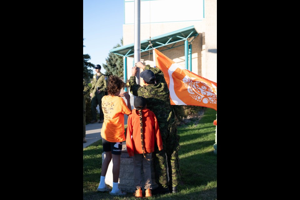 Master Cpl. Jonathan Porter and his children attach the flag to the pole before raising it. Photo courtesy 15 Wing