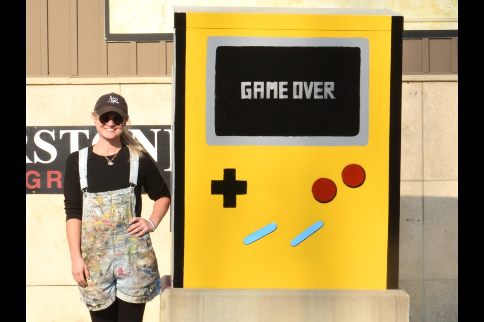 Artist Carly Jaye stands next to one of her downtown creations which gave new life to an otherwise bland electrical box along Manitoba Street on Oct. 17.