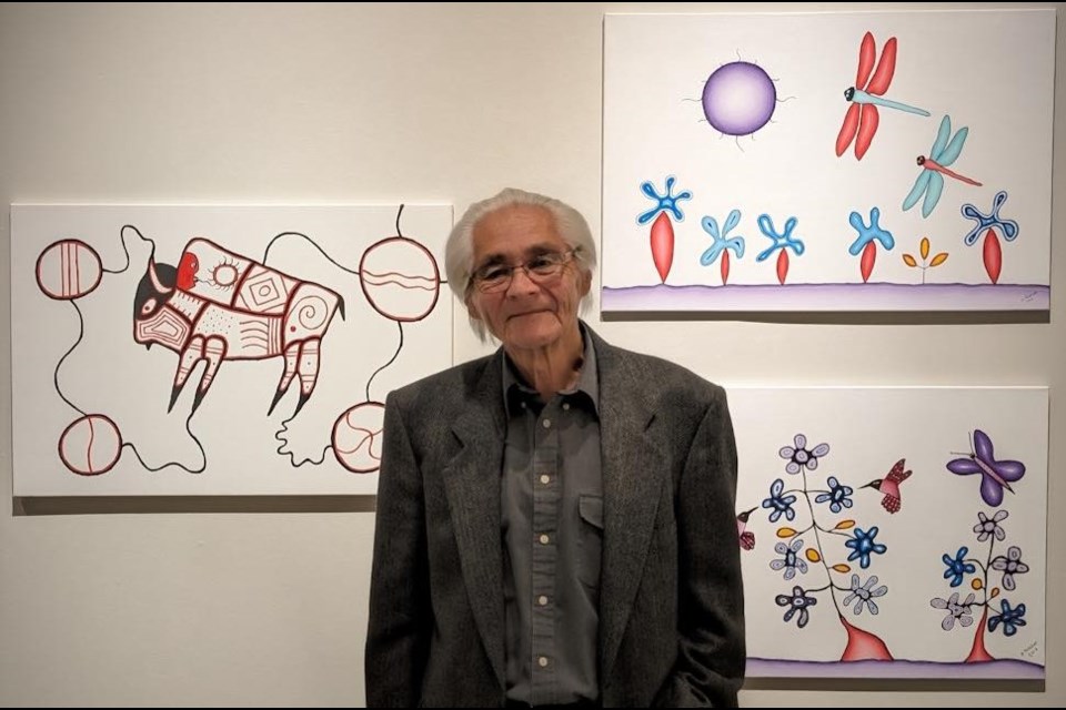 Artist Dave Pelletier stands with some of his paintings at the Wóknaga exhibit at the MJMAG this summer.