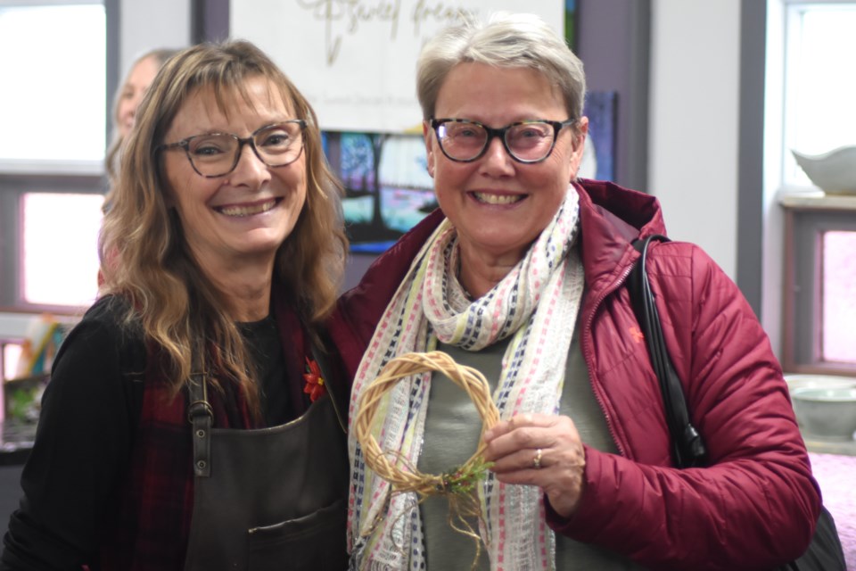 Beth Crabb (left) stands next to a guest displaying her handmade wreath during one of the hourly art demonstrations on Nov. 23.