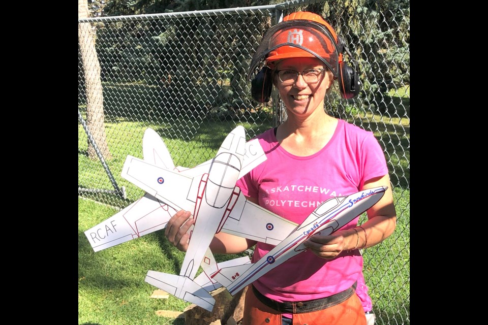 Karen Watson shows the cardboard designs she created to reference when carving the images into a tree in Crescent Park. Photo by Jason G. Antonio 