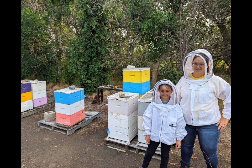 Julie-Anne Howe and her daughter Avery next to a few of their hives