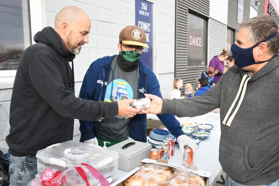 Rob Hoskins (left), business owner of the Comic Book Guy Pop Culture Shop, helps Moose Jaw Families for Change sell burgers as part of a fundraiser for the organization during the shop's grand opening on Oct. 1. Photo by Jason G. Antonio 