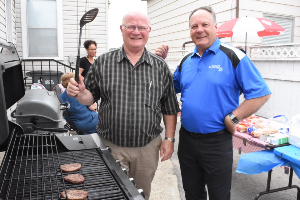 Realtor Jim Low and Mike Botterill, owner of Realty Executives, cook hamburgers and hot dogs during the real estate agency's grand re-opening celebration on July 5 at 70 Athabasca Street West. Photo by Jason G. Antonio