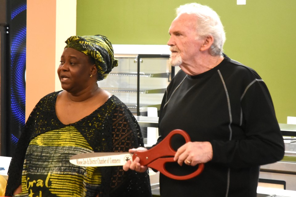 Coral Kitchen owner Temitope Adewumi (left) and Rob Clark (right) with the Chamber of Commerce prepare to mark the grand opening of the mall's newest restaurant on Jan. 25.