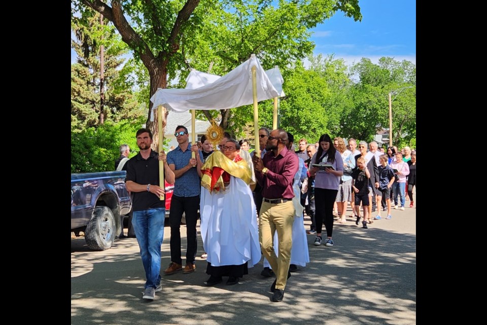 Members of St. Joseph's Roman Catholic Church form a procession through the streets in celebration of Corpus Christi.