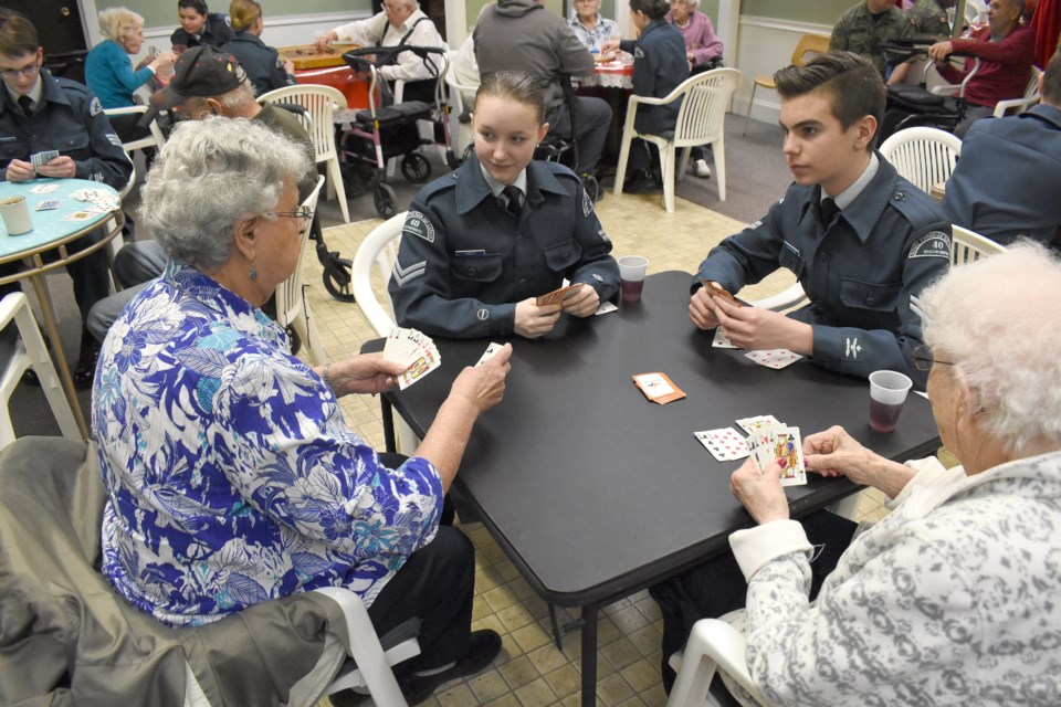 Moose Jaw 40 Snowbird Air Cadets Katherine Furey (back left) and Alex Scidmore play cards with Marie Desruisseaux (front left) and Madeleine Gunningham.