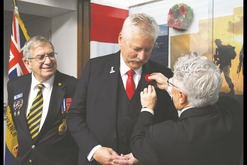 Legion president Robert (Bob) Travale (left) watches as Mayor Clive Tolley receives the first poppy of the campaign from chairwoman Sue Knox. Photo by Jason G. Antonio