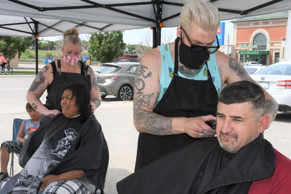 Jason Gauthier (right), founder of charitable initiative StreetCuts Barber, and assistant barber Kyla Jackson (left), work for free on the hair of clients during the first StreetCuts Barber event in Moose Jaw since the pandemic began, on July 12. Photo by Jason G. Antonio 