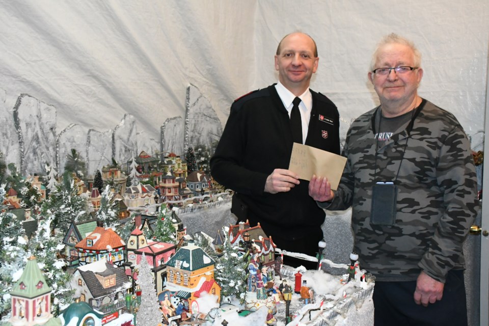 Lt. Lester Ward with the Salvation Army (left) receives $389.50 from Bruce Miller and Erine Allen (not pictured). The proceeds came from the couple's Christmas-themed porcelain village display. Photo by Jason G. Antonio 