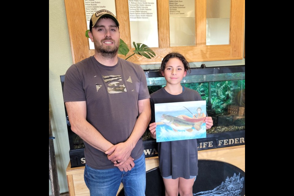 The Saskatchewan Wildlife Federation's Director of Education, Doug Gibson (left) stands with the first-place winner of the 2024 Fish Artwork Contest, Keilani Hill (right).