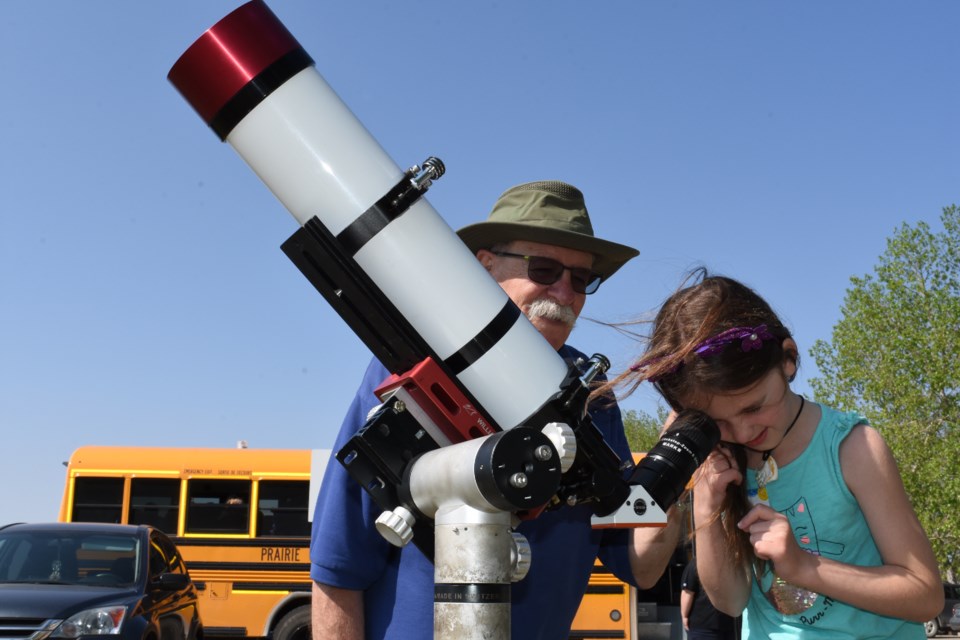 Lexi Sandbeck looks through a solar scope to see the surface of the sun, while being supported by Paul Meyer with the Royal Astronomical Society of Canada — Regina chapter. The solar scope was part of the Western Development Museum's Learning Day on May 29. Photo by Jason G. Antonio 