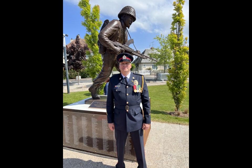 Staff Sgt. Chad Scheske stands in uniform near the statute unveiled near Juno Beach to honour the Regina Rifle Regiment. Photo contributed