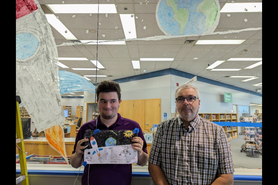 Trea Stafford and Mark Gilliland, with Stafford holding his concept drawing for the mural