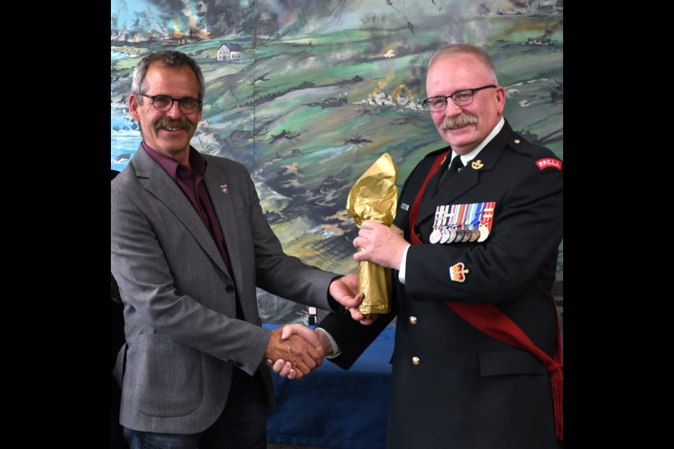 Black Fox Distillery co-owner John Cote (left) presents Warrant Officer Weiss (right) with a bottle of whiskey at the ANAVETS lounge on May 16.