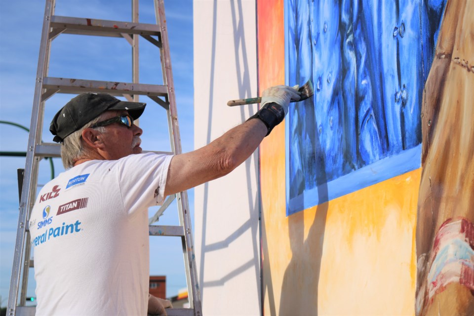 Grant McLaughlin adds a coat of varnish to one of the panels. (Photo by Scott Hellings)