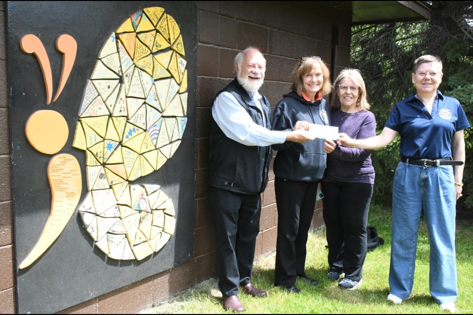 Glenn Hagel (left) and Leanne Pituley (right), members of the Wakamow Rotary Club, present a cheque of $4,097.79 to Journey to Hope members Della Ferguson (second from left) and Donna Atsu-Bowyer (second from right). The group is standing beside a mural that Journey 2 Hope's youth chapter created. Photo by Jason G. Antonio