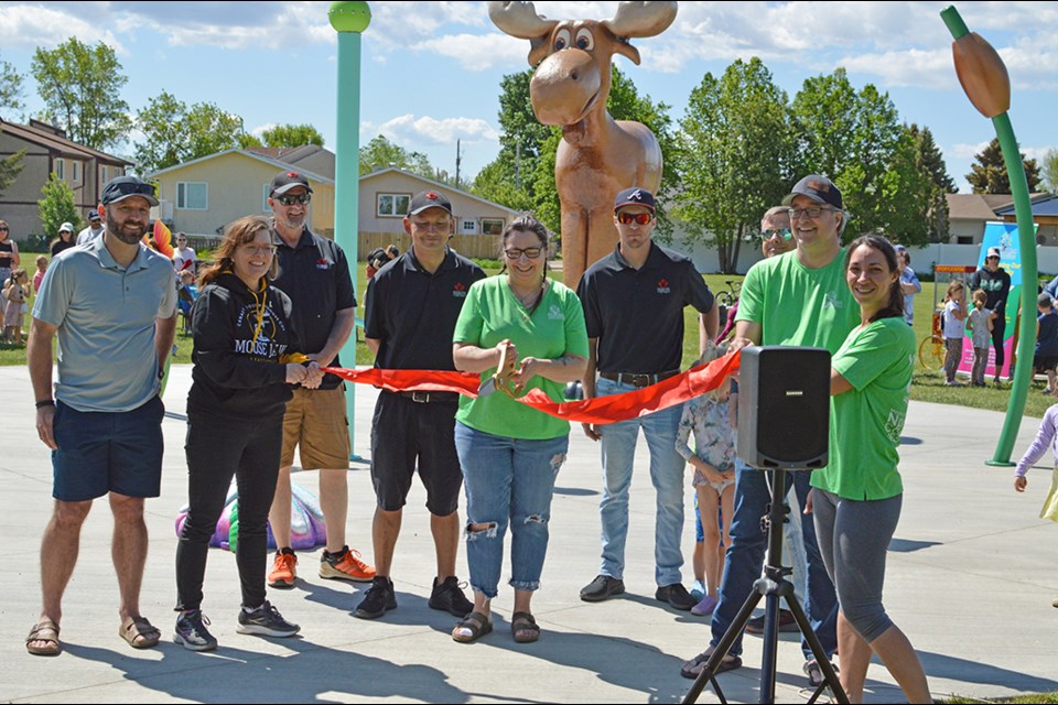 The ribbon cutting with the great moose in the background. From left to right, Derek Blais, Crystal Froese, the Moose Jaw Kinsmen Club, and members from the North West Community Association.