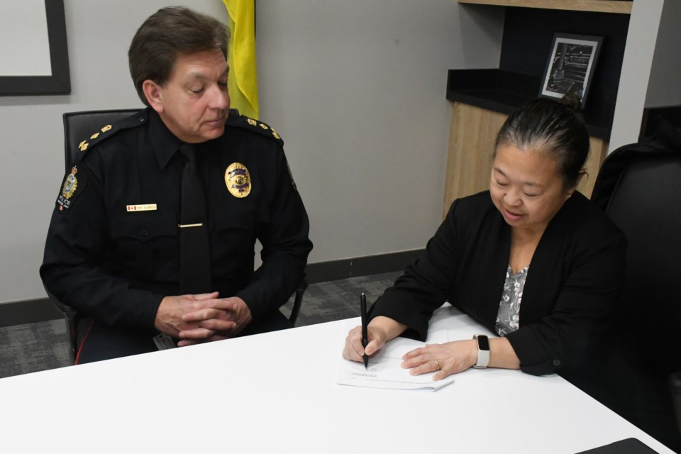 Police Chief Rick Bourassa watches as board chair Mary Lee Booth signs the contract extension. Photo by Jason G. Antonio