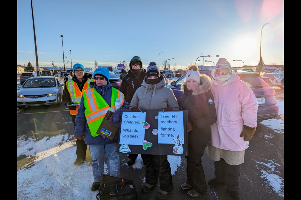 Teachers and supporters pose with custom-made signs in the parking lot of Superstore on Thatcher Drive