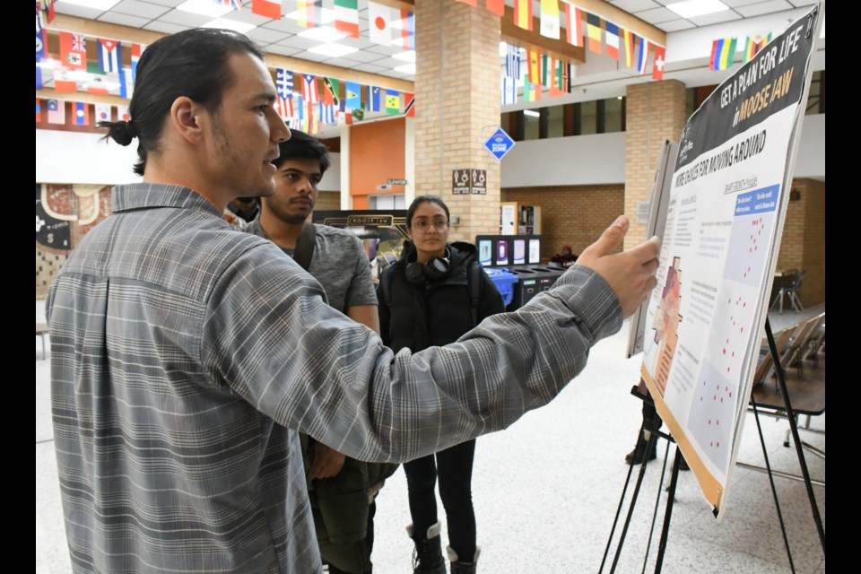 Conor Britton (left), a consultant with firms Crosby, Hanna and Associates and Wallace Insights, speaks to Saskatchewan Polytechnic students about the purpose of the display. Photo by Jason G. Antonio