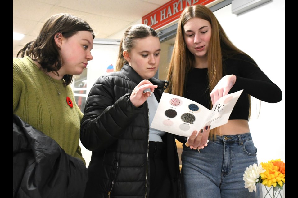 Adysen Moser (right) with Beadlink Creations, shows some of the student-run company's beaded keychains to prospective buyers. Photo by Jason G. Antonio