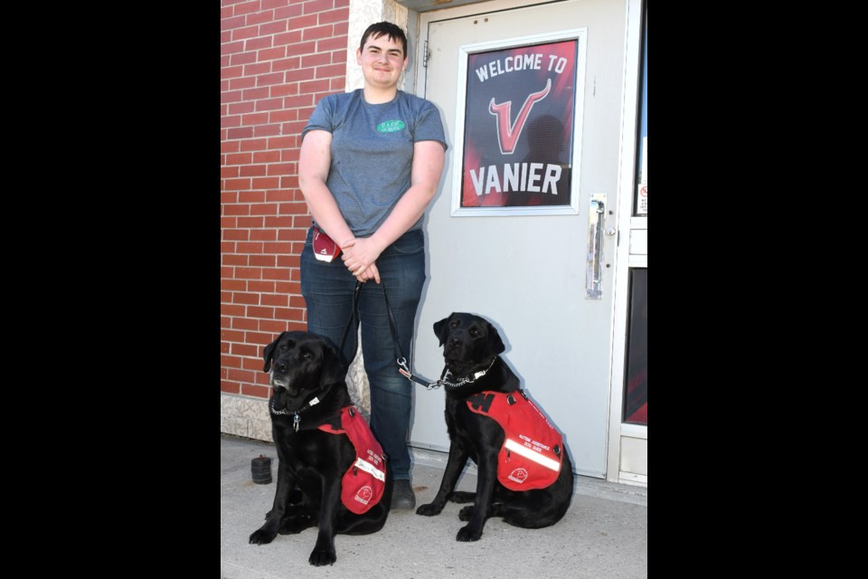 Stephen Walcer, a Grade 12 student at Vanier Collegiate, poses in front of the school with his service dogs Bingo and Doug. Photo by Jason G. Antonio