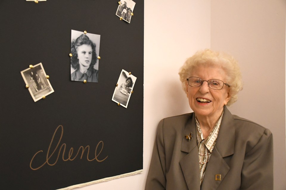 Irene Gaudaur poses next to a photo board showing her as a youngster.