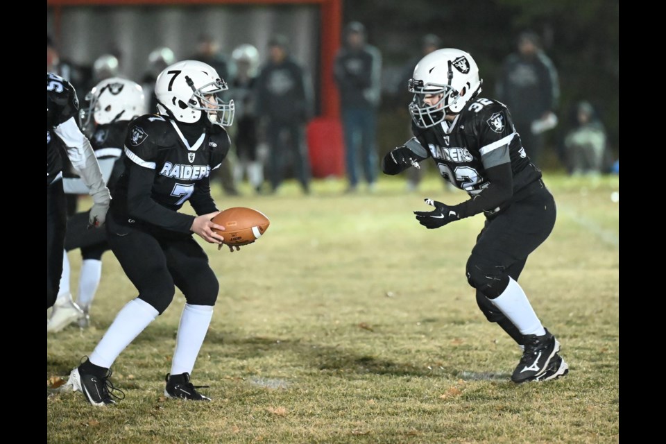 Moose Jaw Raiders quarterback Brooks Michalicz (left) hands the ball off to teammate Evan Audette.