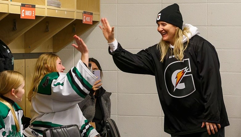 A teammate high-fives four-time Olympic medalist Hayley Wickenheiser during a locker room visit at WickFest 2024.