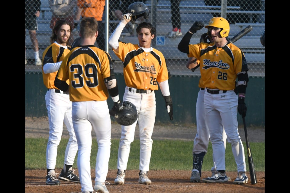 The Miller Express celebrate at the plate with Austin Gurney after Gurney hit his second home run of the season.