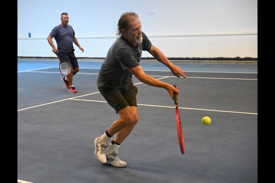 Brian Swanson (foreground) plays a shot down in close to the net as his doubles partner Scott Evans watches on - MJ Independent photo