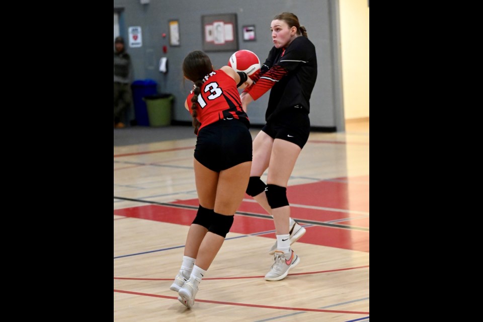 Two Vanier Collegiate volleyball players attack the ball. 