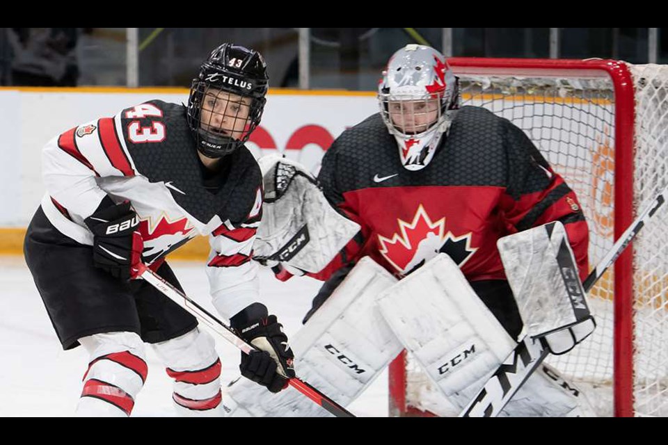 Moose Jaw Warriors goaltender Jackson Unger keeps an eye on the action with Team Canada forward Kristin O’Neill in front of the net.