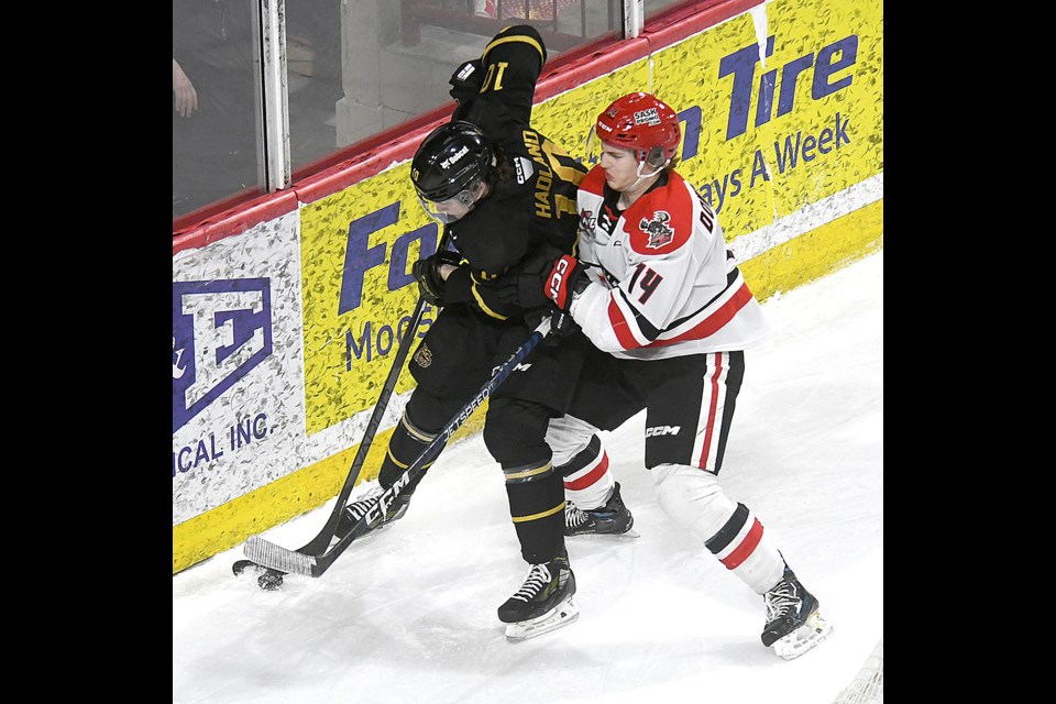 Warriors defenceman Logan Dowhaniuk takes Caleb Hadland into the end boards.