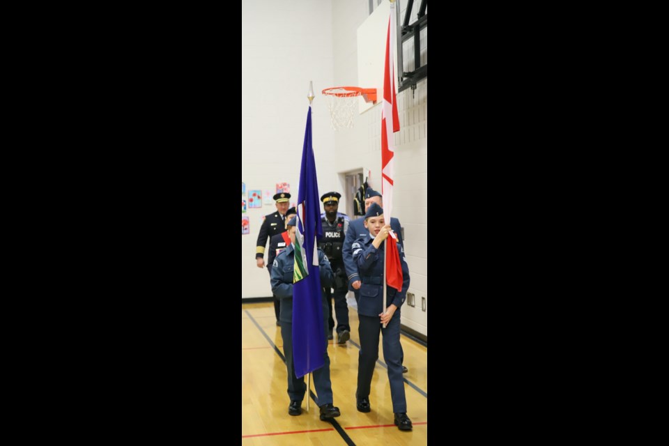 The colour party marches into the school gym for the Remembrance service.
