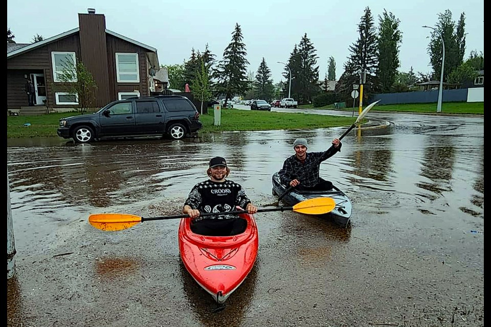 A pair of kayakers are all smiles after enjoying a quick ride down an Innisfail street following a hard but short rainfall during the evening of May 22. Town of Innisfail staff say there was no reports of any damage and just a minor clean-up. Facebook/Innisfail Bulletin.